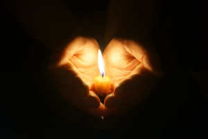 A candle held in a hand | NICRC