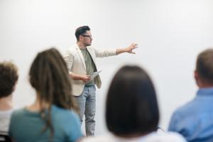 A man presenting his work to a room of people | NI CRC