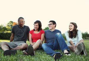 Four smiling people sitting on together on the grass | NI CRC