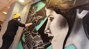 A man painting graffiti in a gallery | CRC NI